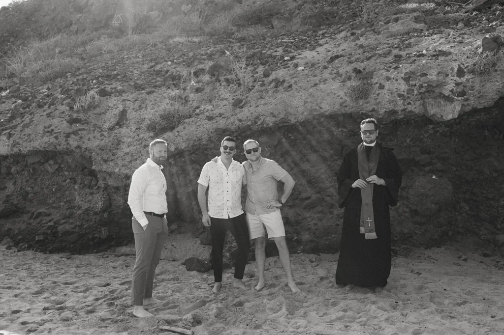 the groom and his friends at the beach waiting for the bride at an isolated beach, white sand and mountains in the back.