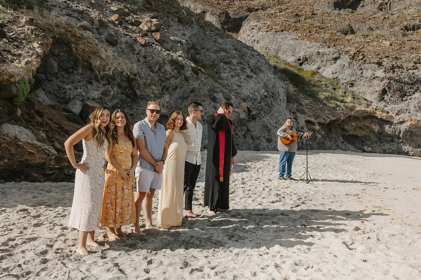 group of friends of the bride and groom at the beach eloping in Los Cabos. mountains in the back.