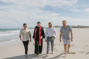 groom and his friends walking at the beach.