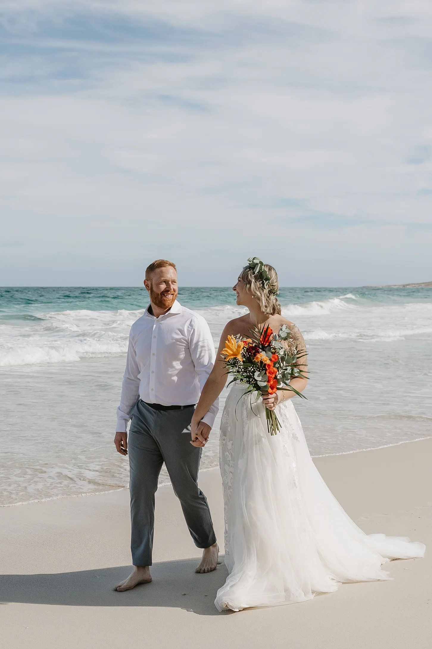 couple walking holding hands at Tecolote beach.