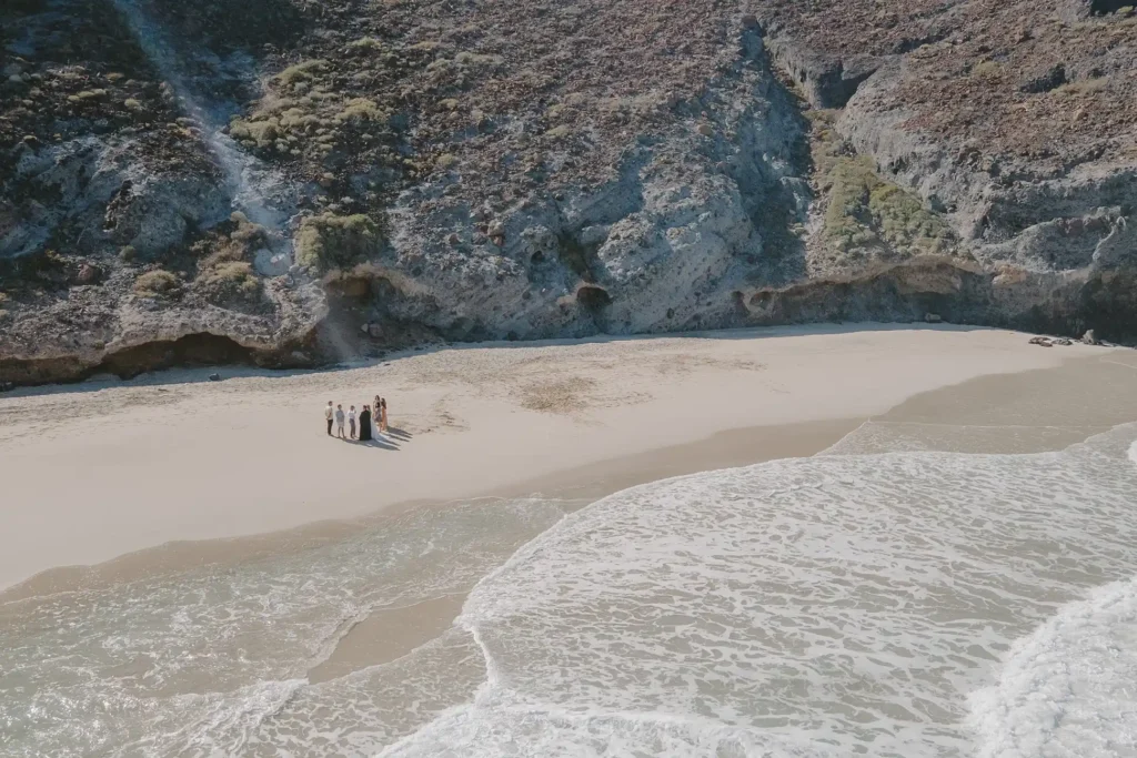 mountains, blue beach and a couple eloping, is a drone photo. 
