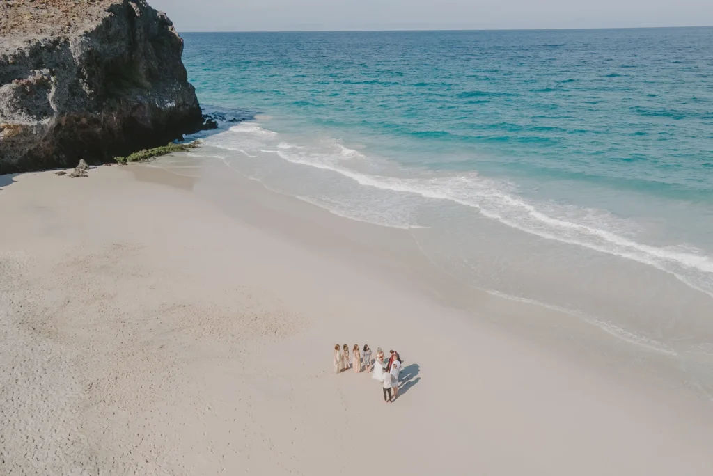 drone photo, blue beach a mountain and the beautiful white sand a couple eloping with their closest friends. 