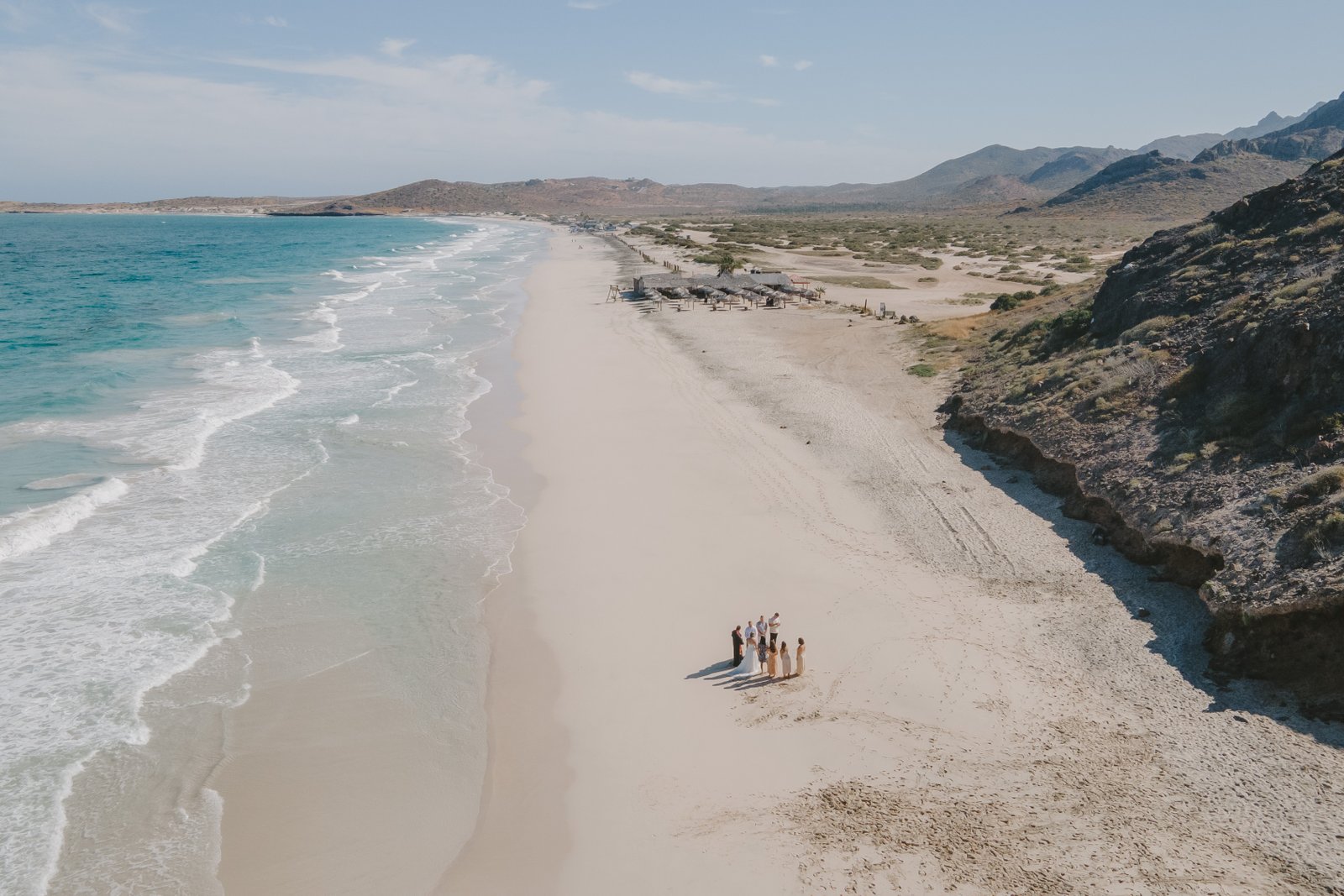 a couple eloping at a beautiful blue beach with their close friends in La Paz, Baja California Sur. is a drone photo, La Paz photographer.