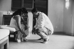 groom helping the bride getting ready for their intimate wedding in mexico. 