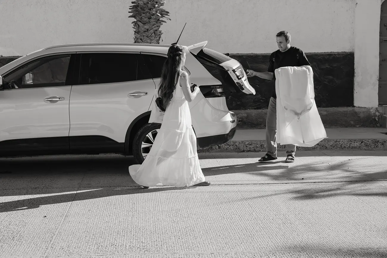 bride and groom getting their stuff ready at their car to head over to the beach.