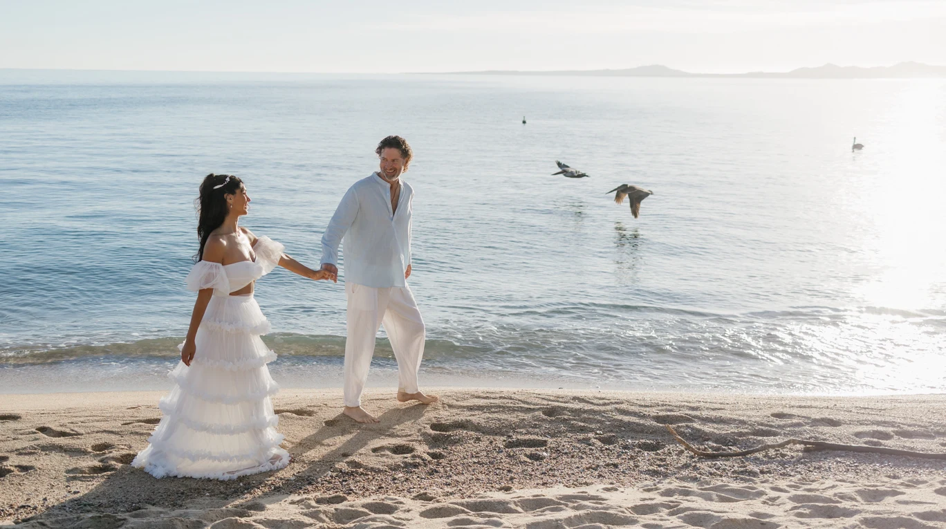 couple walking holding hands by the beach eloping in los cabos mexico.